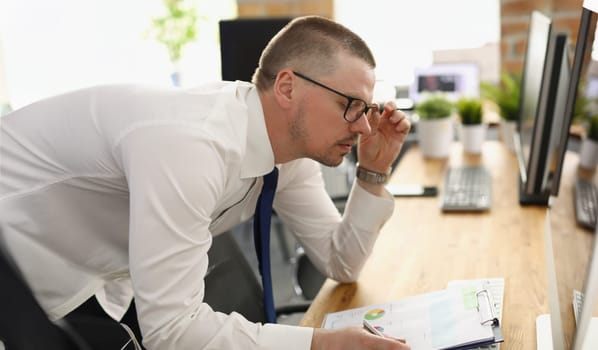 A man in the office is editing a report with a diagram, close-up, blurry. Changes in the financial statement of the company