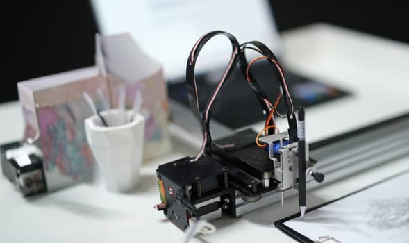 3d printer draws with a pencil on paper, close-up. A modular device with artificial intelligence. Reproduction of the digital model