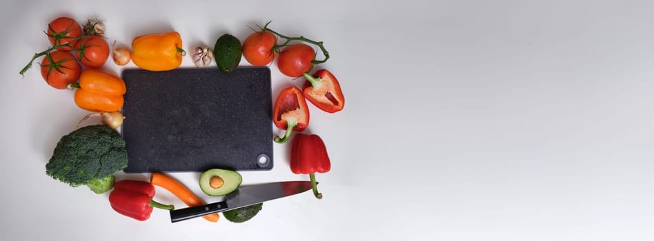 Vegetables around a black kitchen cutting board, top view, mockup. Cutting various vegetables on the table