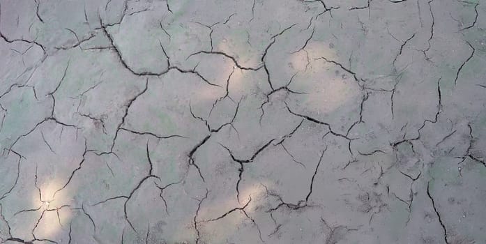 Sun beams on dry cracked gray ground, close-up. Soil erosion, drought, poor ecology, lack of rainfall