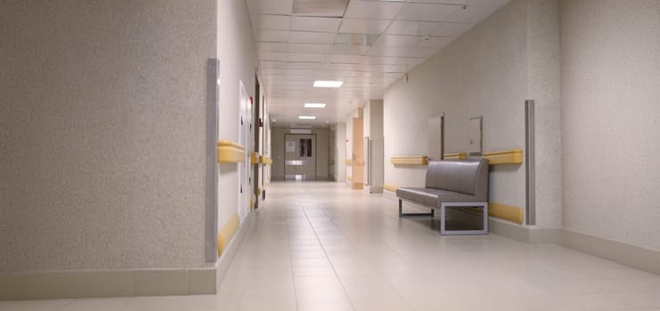 An empty gray corridor of an office building, nobody. Lighting on the hospital floor, intensive care. Hall of the clinic