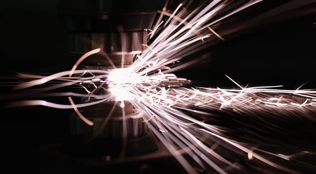 Sparks from metal contact on a machine tool on a dark background, close-up. Iron cutting, metallurgical process, manufacturing