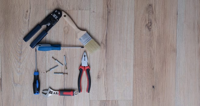 A set of tools for home renovation lies on the laminate. Adjustable wrench with screwdriver. Pasatizhi and paint brush.
