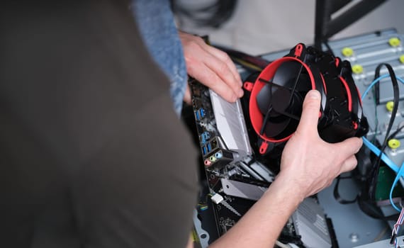 The repairman took the cooler out of the computer, close-up. Processor repair, pc cooling system upgrade