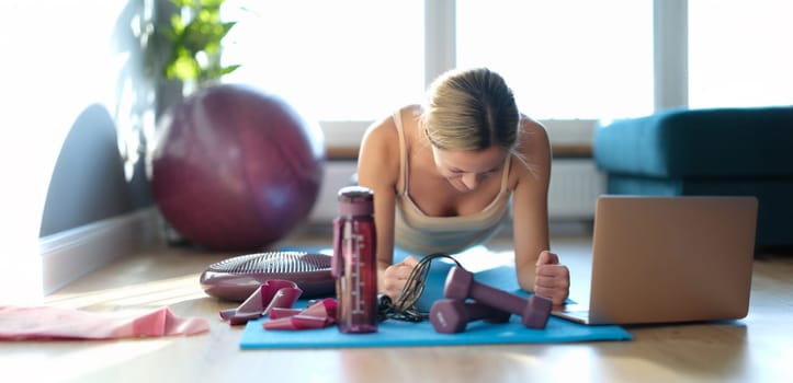 Woman on the floor doing plank exercise on her arms, close-up, sunny. Exercise tightens the abs and shapes the buttocks