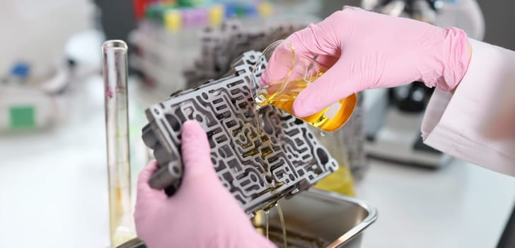 The laboratory assistant pours a yellow liquid on the metal, close-up. Chemical reaction, scientific experiment