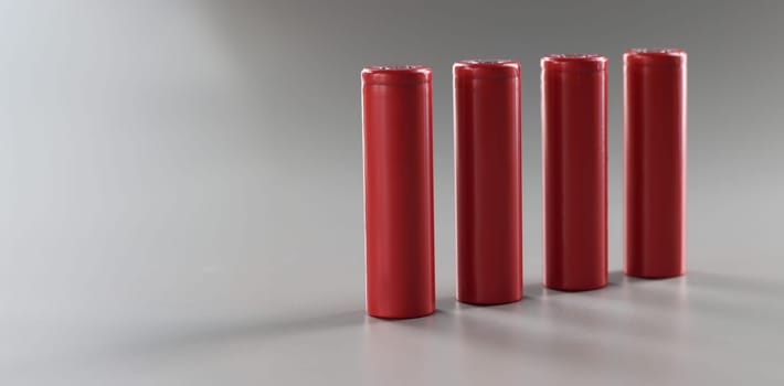 Red batteries stand in a row on a gray background, close-up. Rechargeable alkaline battery. Disposal lithium material