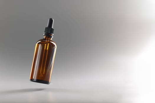 Brown transparent bottle with a pipette on a gray background, close-up. Dropper for medicines. Drop dispenser