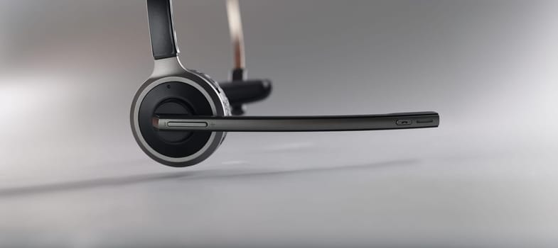 Wireless headset with a microphone on a gray background, close-up. Call center equipment, one ear. Working from home