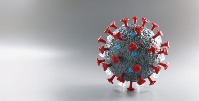Plastic 3d model of coronavirus on a gray background, close-up. Search for a vaccine against omicron. Covid treatment. PCR test