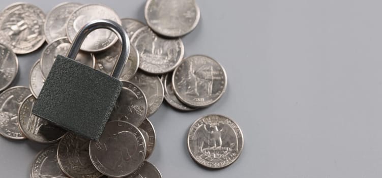 Gray padlock on old coins, close-up, gray background. Concept hidden treasure, found treasure, money in a cell