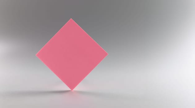 Pink blank paper rhombus on a gray background, close-up. beautiful design element, sheet sticker, branding