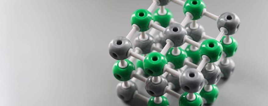 Plastic model of a molecule, crystal lattice of an atom on a gray background, close-up. Organic chemistry