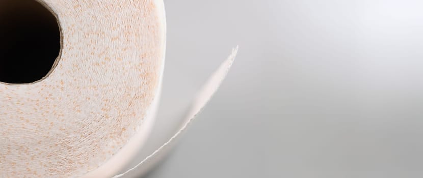 Close-up of a roll of soft toilet paper on a gray background. Texture of loose white kitchen napkin, recyclable