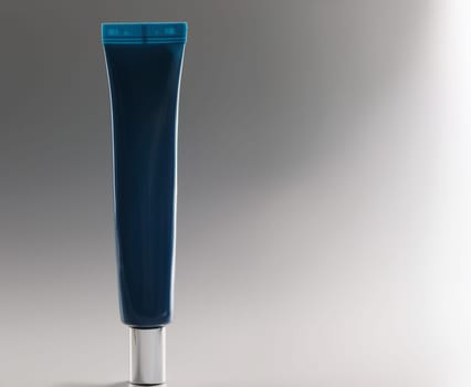 Blue tube with cream on a gray background, close-up. Facial cosmetics, non-comedogenic, skincare and makeup products