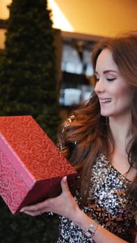 Girl holding Christmas present near New Year tree. Happiness emotions. High quality photo