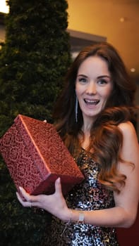 Girl holding Christmas present near New Year tree. Happiness emotions. High quality photo