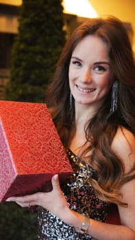 Girl holding Christmas present near New Year tree. Happiness emotions. High quality photo