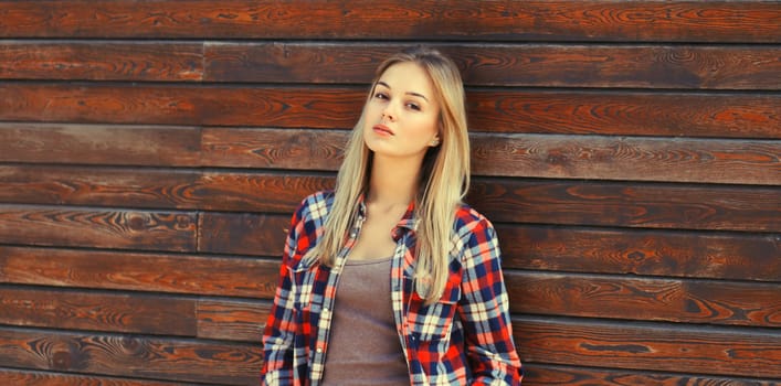 Portrait of beautiful caucasian blonde young woman in casual checkered shirt in the city