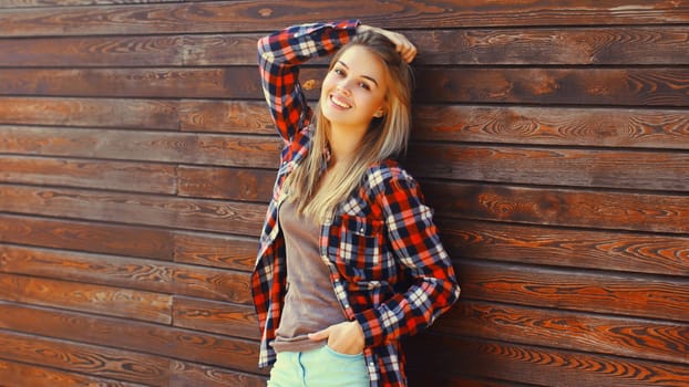 Portrait of beautiful caucasian blonde smiling young woman in casual checkered shirt in the city