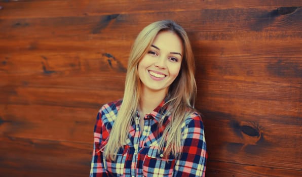 Portrait of beautiful caucasian blonde smiling young woman in casual checkered shirt in the city