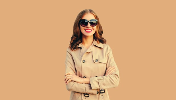 Portrait of beautiful woman posing with crossed arms wearing coat jacket isolated on brown studio background