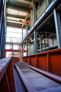 A conveyor belt transports sand inside an industrial facility with visible structural elements