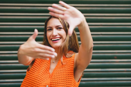 Urban portrait of a latin woman framing with hands smiling at camera
