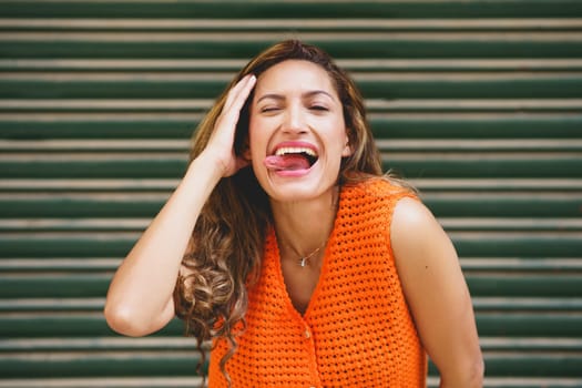 Urban portrait of a latin beauty woman flirting sticking the tongue out smiling at camera