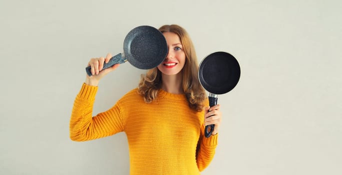 Cooking mood, portrait happy smiling young woman housewife with empty frying pan on gray background
