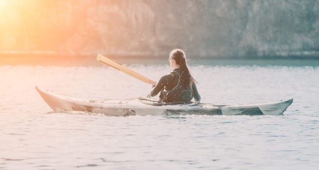 Happy smiling woman in kayak on ocean, paddling with wooden oar. Calm sea water and horizon in background