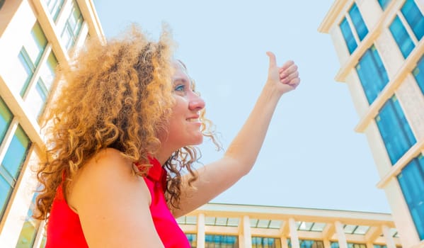 Portrait happy fasion woman shows thumb up against the sky and looking and looks sideways and up. concept of good and happy