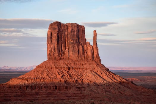 Stunning view of West Mitten Butte in Monument Valley, Arizona, at dusk. The iconic red rock formation glows in the soft evening light, showcasing the natural beauty of the American Southwest - USA