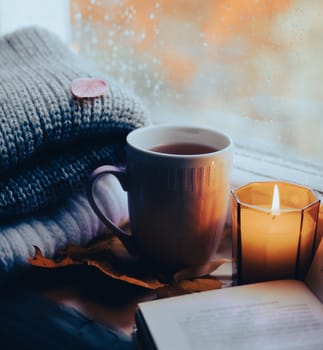 A burning candle on the window is autumn . the comfort of home . autumn comfort . autumn mood. The chondra .
