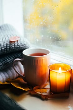 A burning candle on the window is autumn . the comfort of home . autumn comfort . autumn mood. The chondra .
