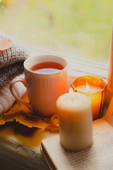 A burning candle on the window is autumn . the comfort of home . autumn comfort . autumn mood. The chondra .