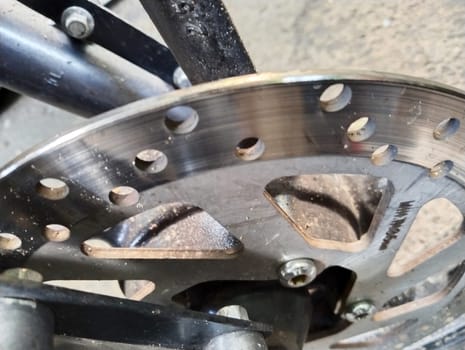 A detailed inspection of a bicycle disc brake rotor showcases the metal surface and holes used for ventilation and cooling.