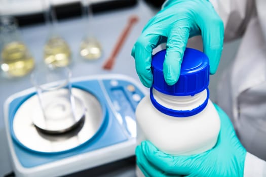 Close-up researcher opens the bottle with the reagent in a chemical laboratory.