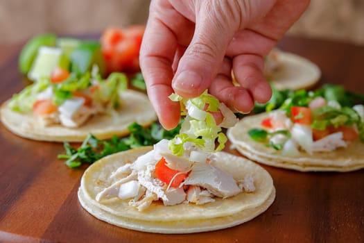 A close up studio photo of putting shredded lettuce on a street taco.