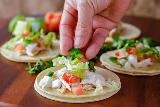 A close up studio photo of putting chopped peppers on a street taco.