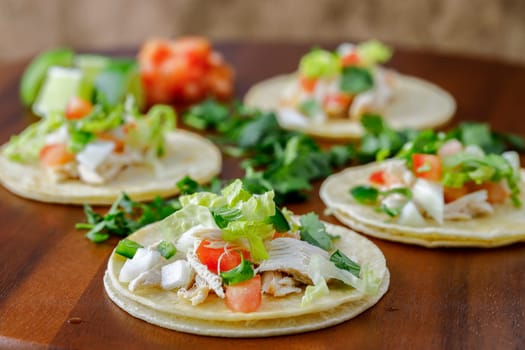 A close up photo of four street tacos displayed on a wooden board.