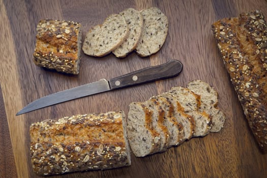 An overview of whole grain baguette and baguette slices with a knife.