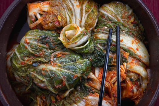 A studio overview of whole kimchi freshly made stacked inside a large pot. A staple side dish in Korea.