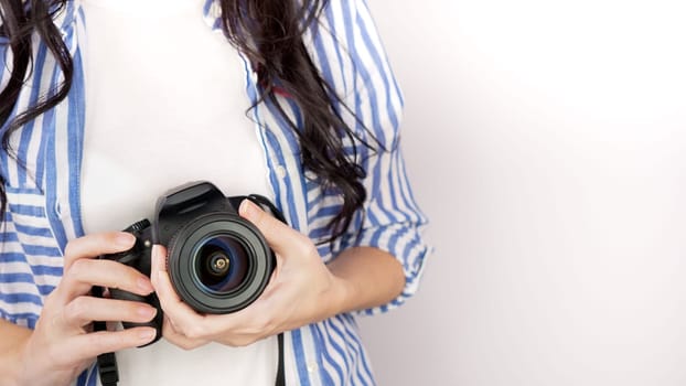 Photographer holding dslr camera. Self portrait, front view. Faceless nice woman with brown red hair in a tshirt with hands holding photo camera white background