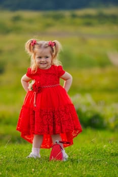 little girl in a red dress walks on the lawn