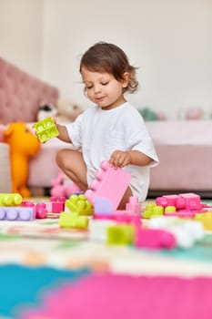 cute baby girl playing with colorful toys bricks at home