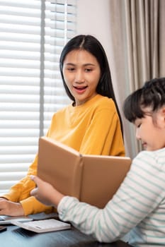 A mother and daughter share a special moment reading a book together in a bright and cozy living room.