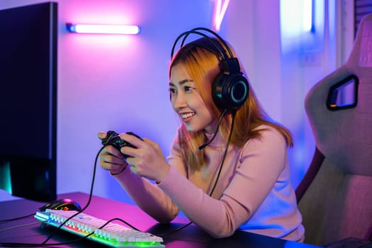 You win. Gamer using joystick controller plays online video game with computer neon lights very determined, woman wear gaming headphones playing live stream esports games console at home