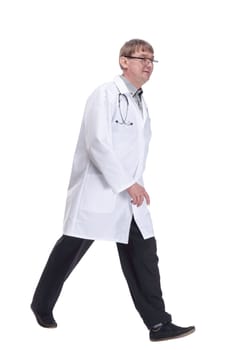 in full growth. friendly doctor with a stethoscope striding forward .isolated on a white background.