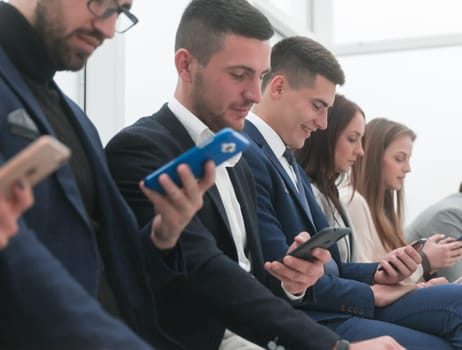 close up. group of young business people looking at their smartphone screens.